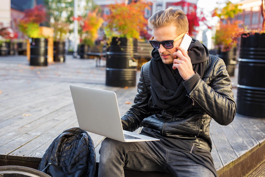 Millennial on phone and working on laptop